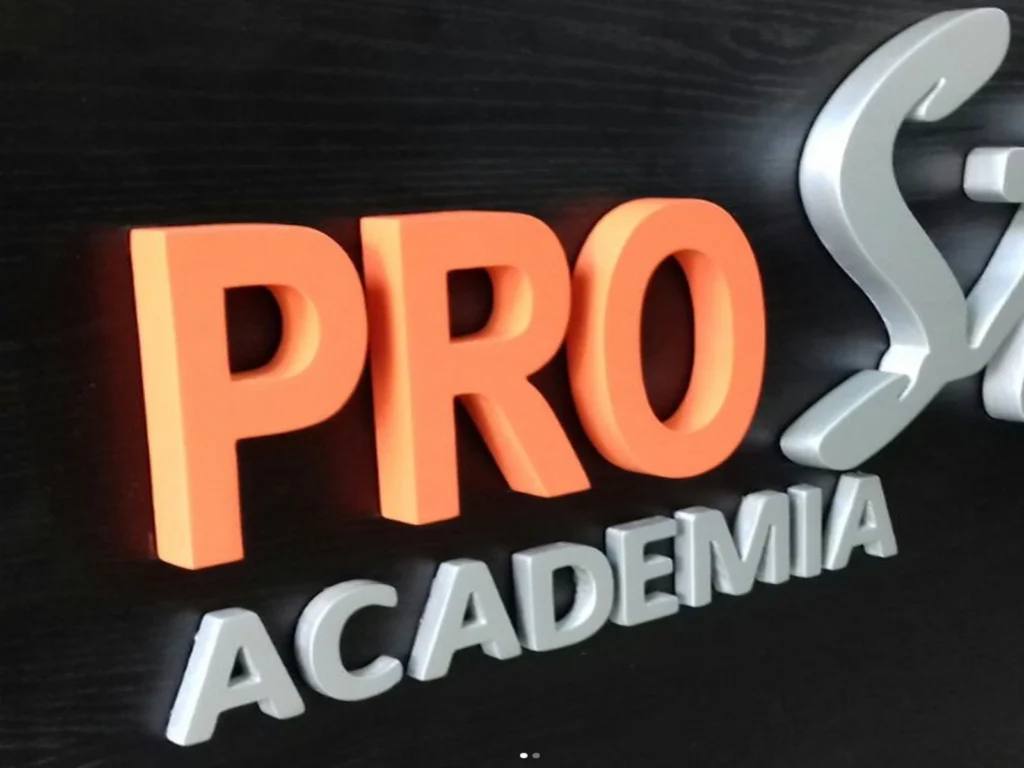 Letra caixa da Pro Academia em laranja e prata instalada na fachada