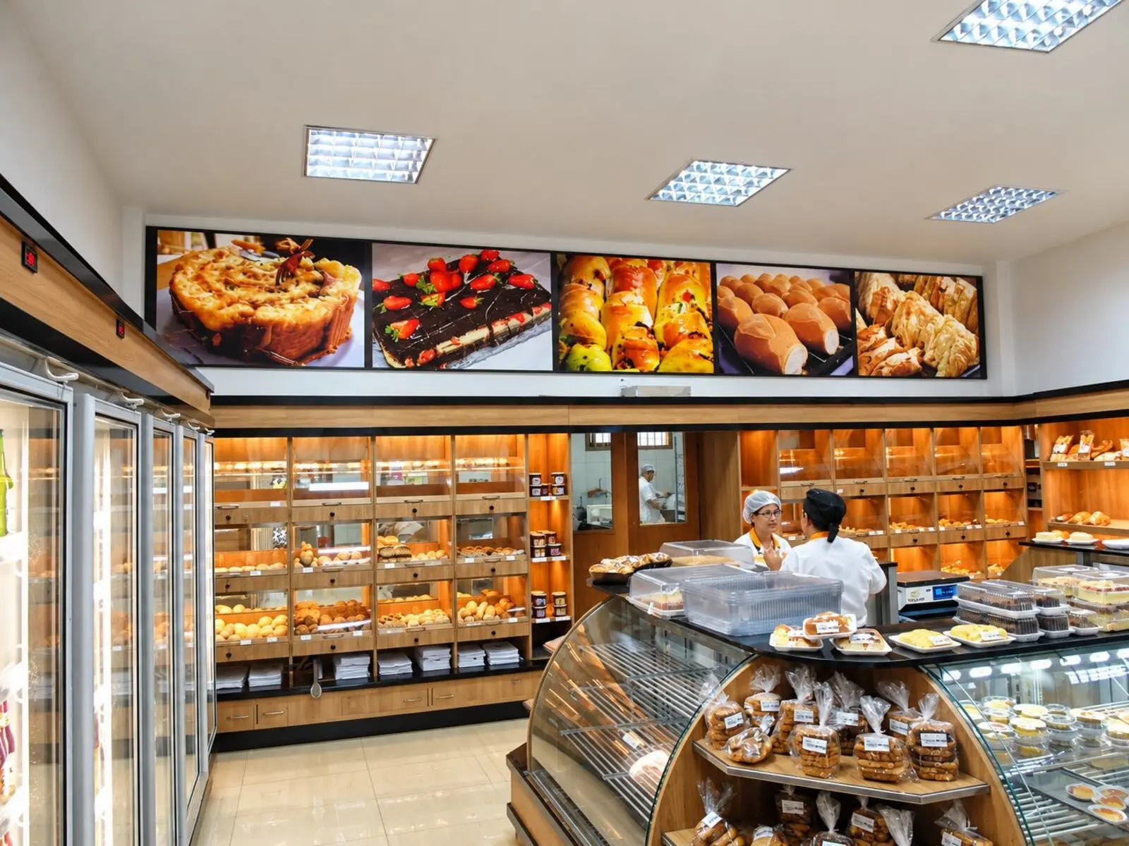 Interior de padaria com painéis iluminados de produtos instalados acima do balcão