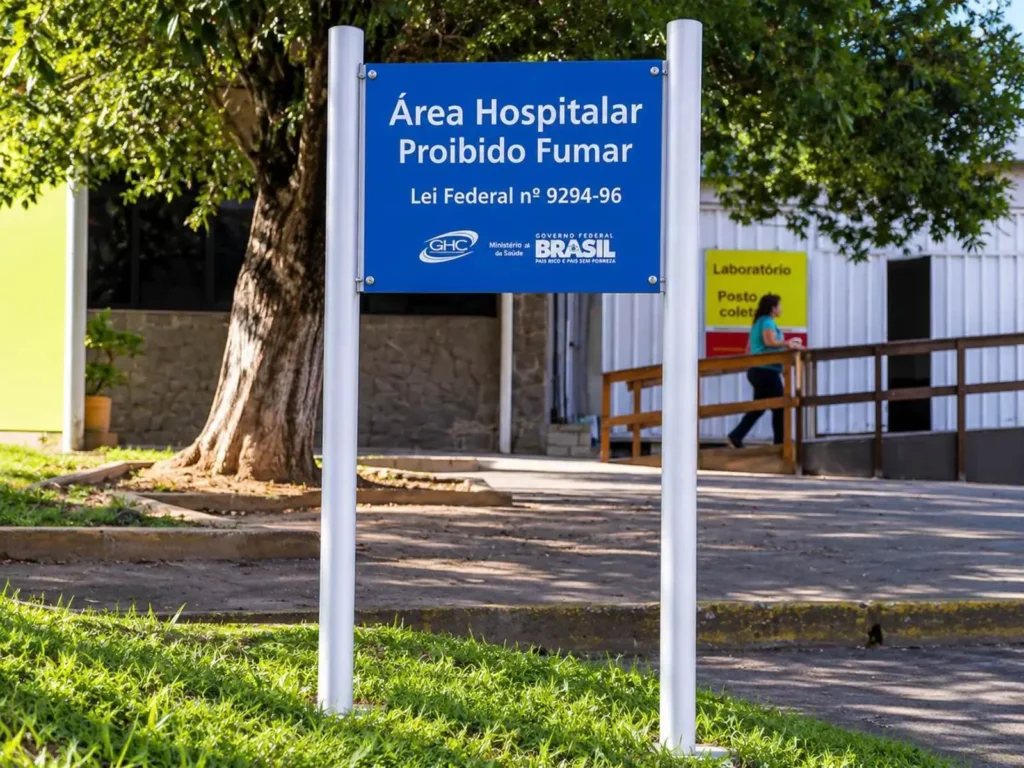 Placa de sinalização de área hospitalar com proibição de fumar instalada em pedestal duplo no GHC
